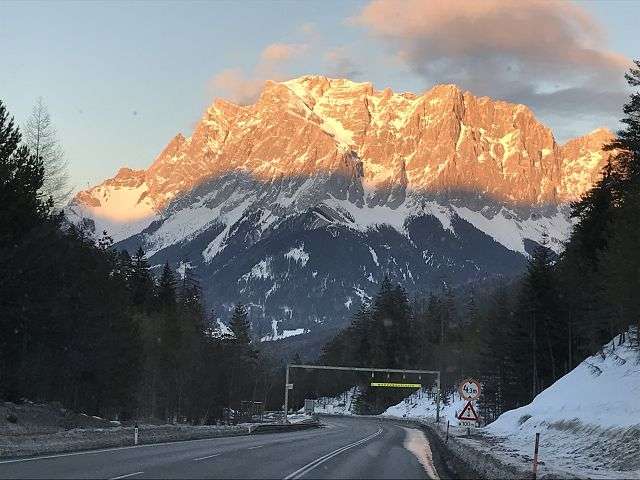 Berg im Sonnenaufgang mit schneebedeckter Straße im Vordergrund