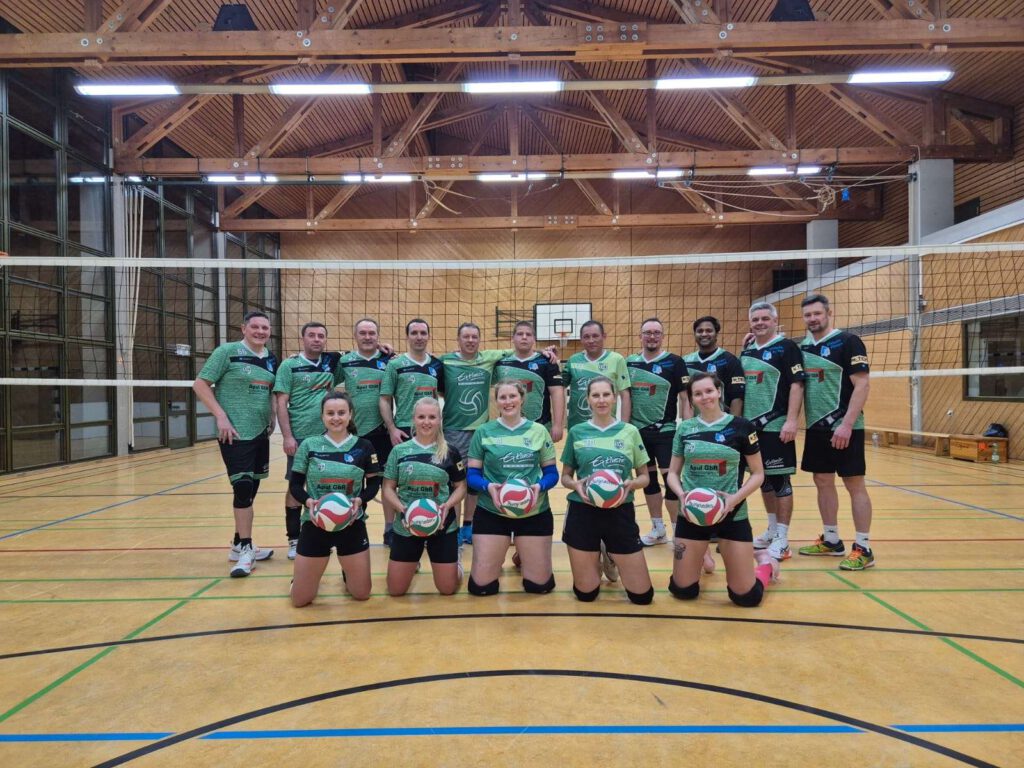 Mannschaftsfoto eines Volleyballteams in einer Sporthalle.