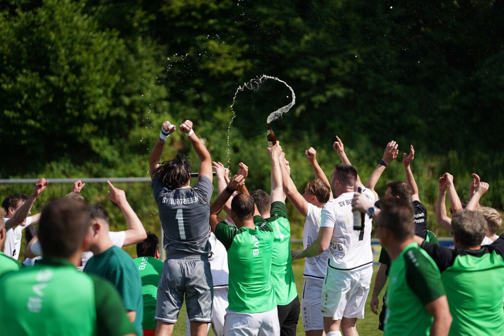 Fußballteam feiert Sieg auf dem Spielfeld.
