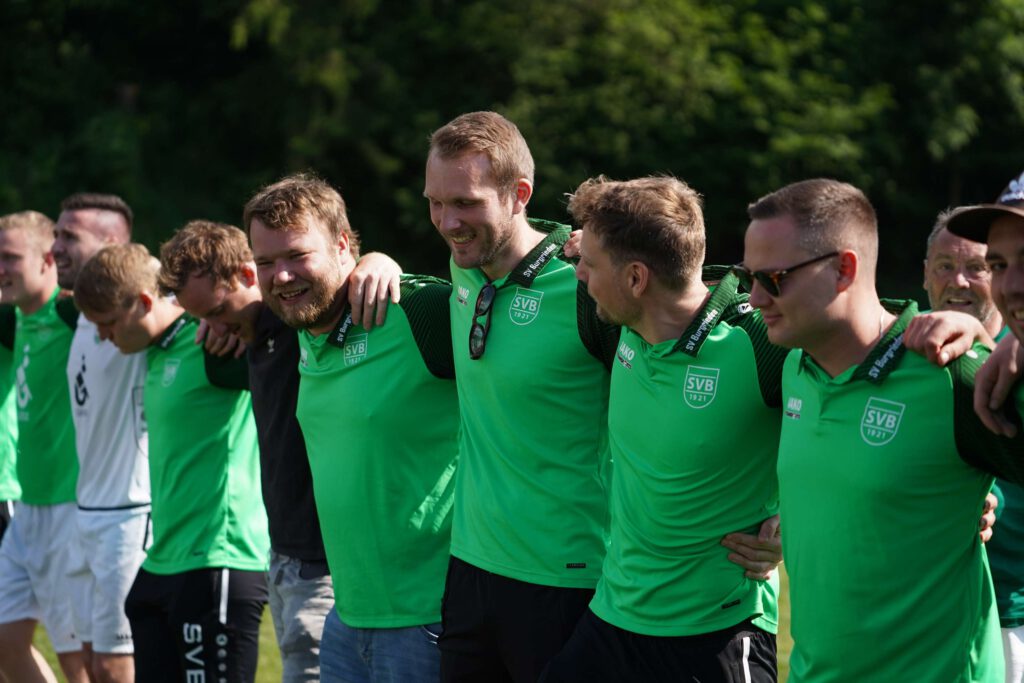 Gruppe von Fußballspielern in gruenen Trikots steht nebeneinander.