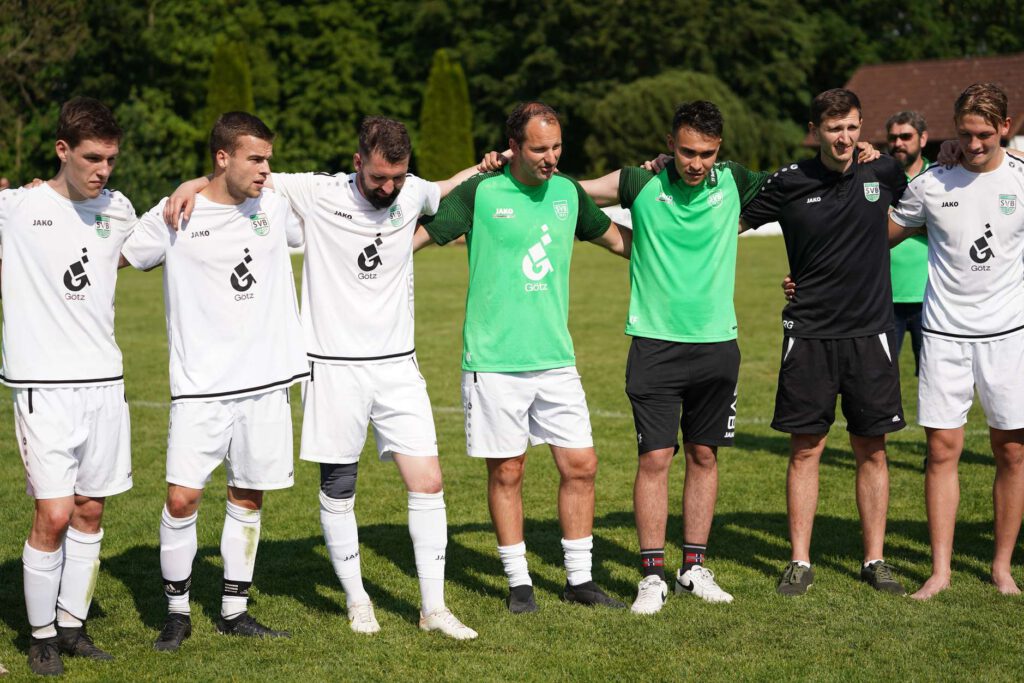 Eine Gruppe von Fußballspielern steht auf einem Rasenplatz in einer Linie zusammen.