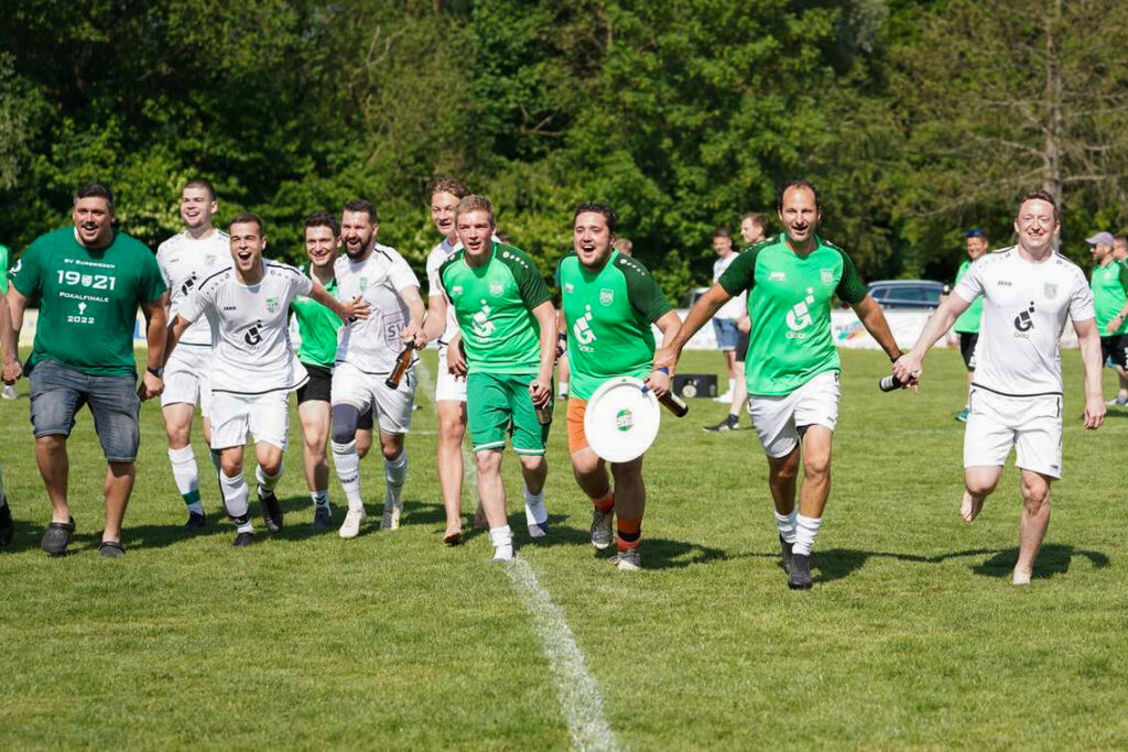 Eine Gruppe von Fußballspielern in gruenen und weißen Trikots auf einem Spielfeld.