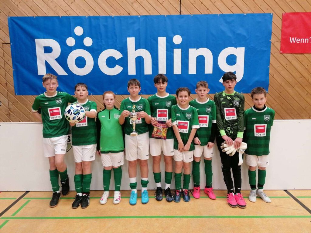 Ein Jugendfußballteam posiert fuer ein Gruppenfoto in der Halle.