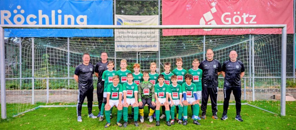 Eine Jugendfußballmannschaft posiert fuer ein Gruppenfoto vor einem Fußballtor.