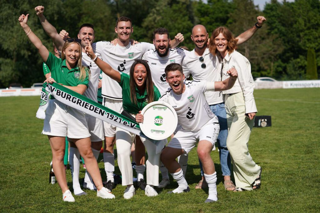 Eine Gruppe von Menschen feiert einen sportlichen Sieg im Freien.