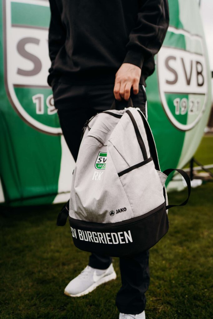 Person traegt SVB-Sporttasche vor einem gruenen Hintergrund.