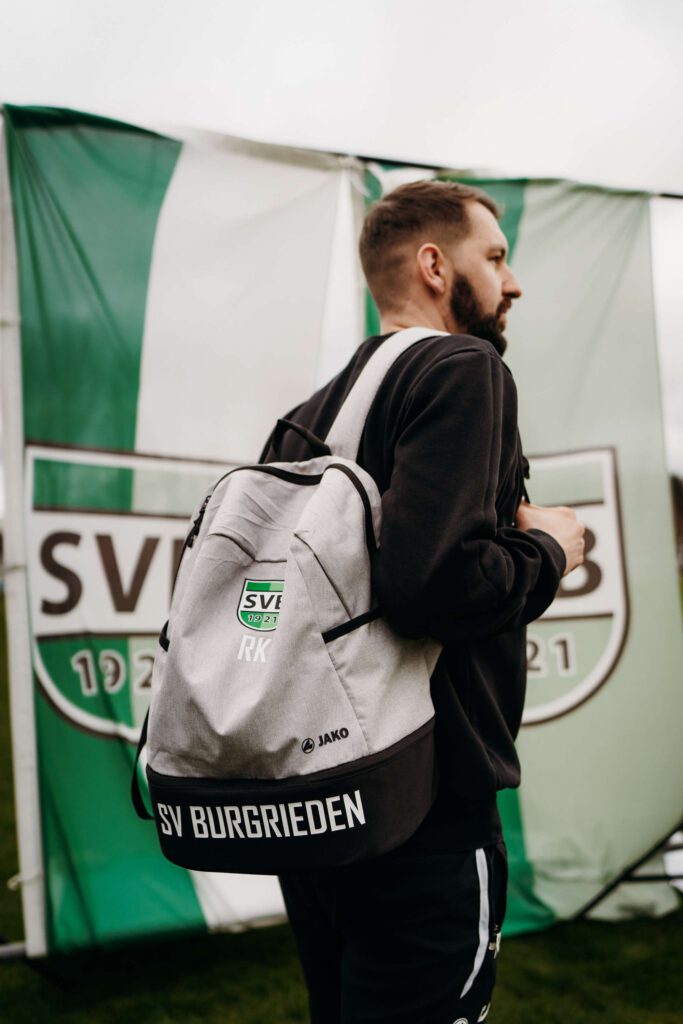 Mann mit Rucksack vor SVP OBBESHEIM Banner